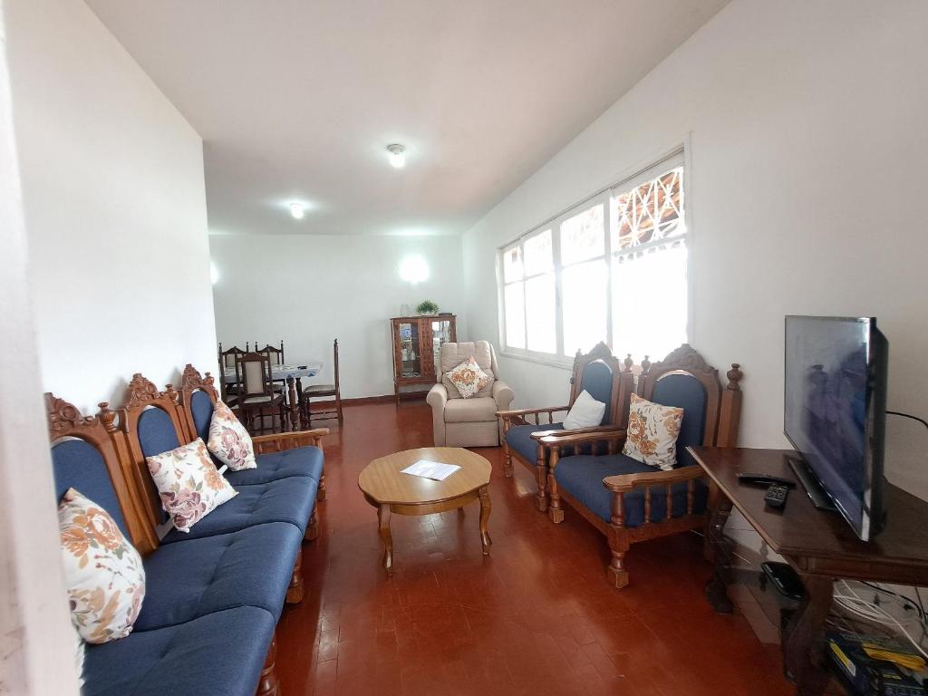 uma sala de estar com sofás azuis e uma televisão em 3 QTS Churrasqueira Garagem perto do Forte e Ilha do Japonês em Cabo Frio