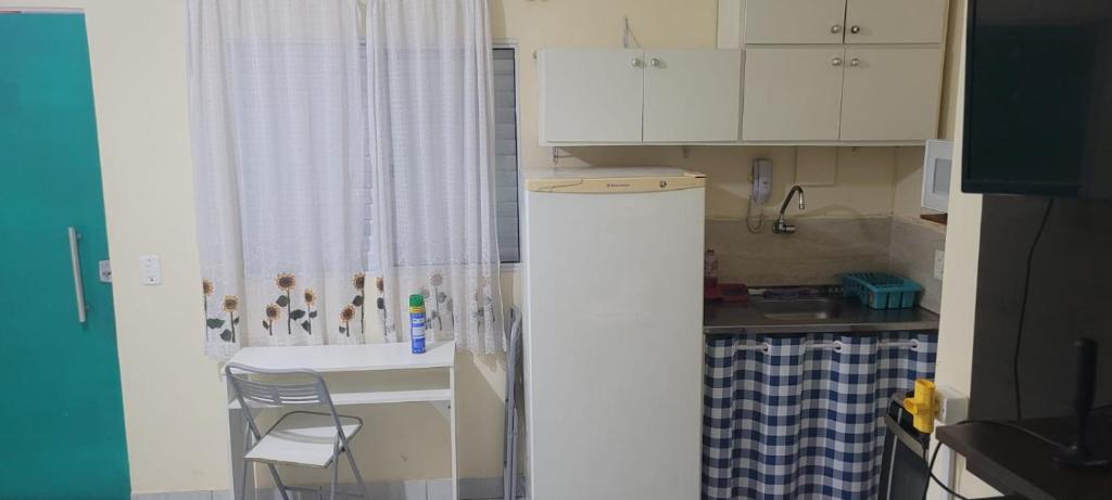 uma pequena cozinha com armários brancos e um lavatório em Kitinet Central em Belo Horizonte