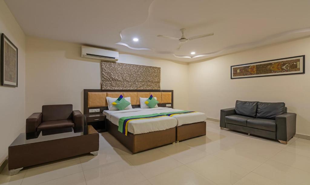 a bedroom with a bed and a chair in it at Treebo Trend Emerald in Hyderabad
