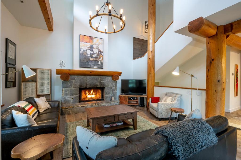 a living room with a couch and a fireplace at Newly renovated 4-bed, bath ski-in, ski-out with fireplaces, private hot tub, and private garage! in Whistler