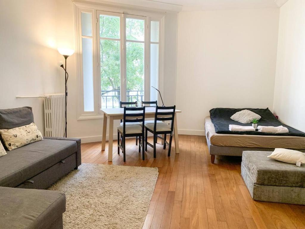 un soggiorno con un divano e un tavolo con sedie di Studio de charme Tour Eiffel a Parigi