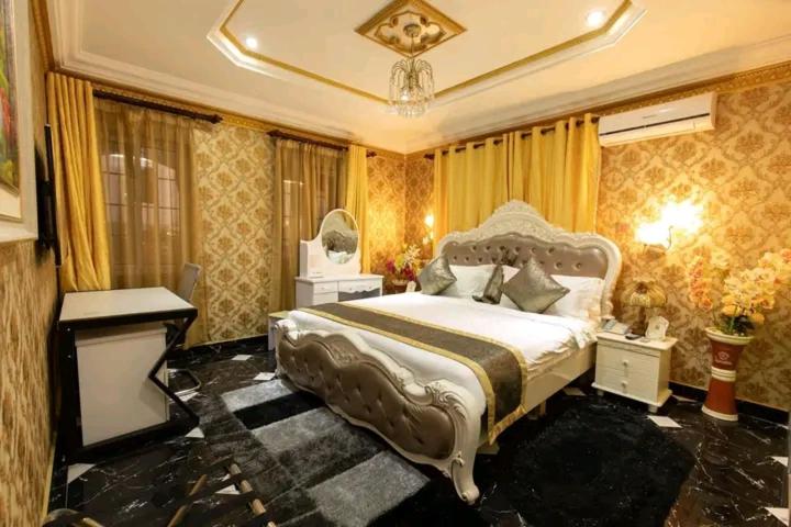 1 dormitorio con 1 cama grande y piano en AG HOTEL AND SUITES, en Accra