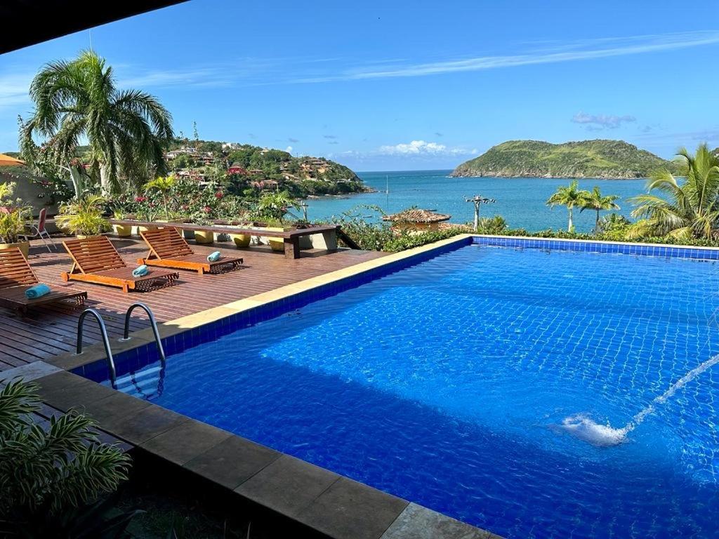 a swimming pool with a view of the ocean at Casa de CINEMA 3 suites, 50m da Praia da Ferradura in Búzios