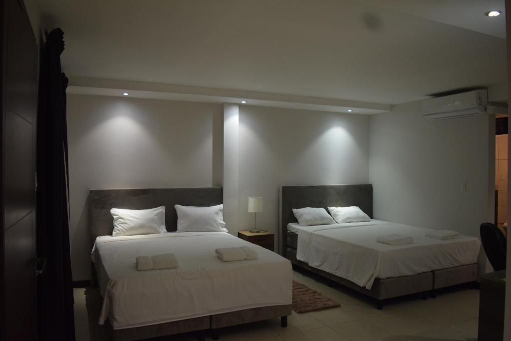 a bedroom with two beds with white sheets at Hotel RITZZ in Paramaribo