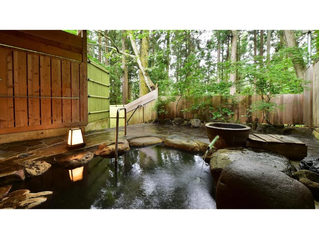 Oyado Kotobuki - Vacation STAY 97600v في Yokokura: حديقة خلفية بها بركة بها مرحاض وسياج