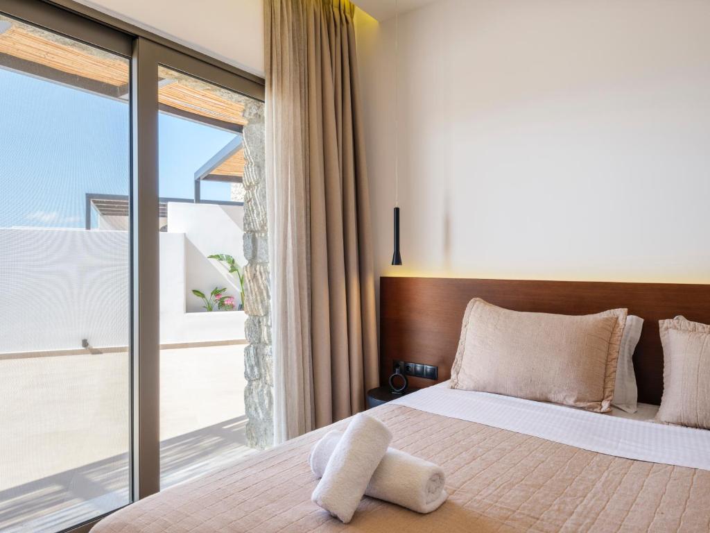 a bedroom with a bed and a large window at Villa Evi & Suites in Mikonos