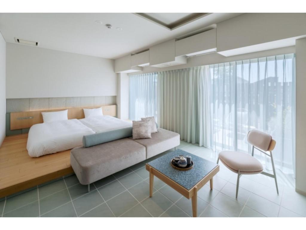 ITOMACHI HOTEL 0 - Vacation STAY 97823v في Saijo: غرفة نوم بسرير واريكة وطاولة