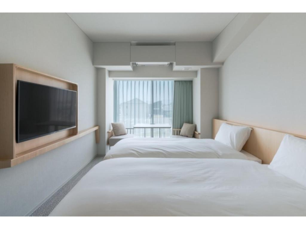 a hotel room with two beds and a flat screen tv at ITOMACHI HOTEL 0 - Vacation STAY 97646v in Saijo