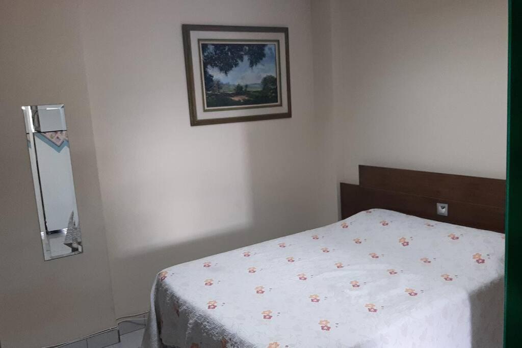 um quarto com uma cama e uma fotografia na parede em Kitinet Central em Belo Horizonte