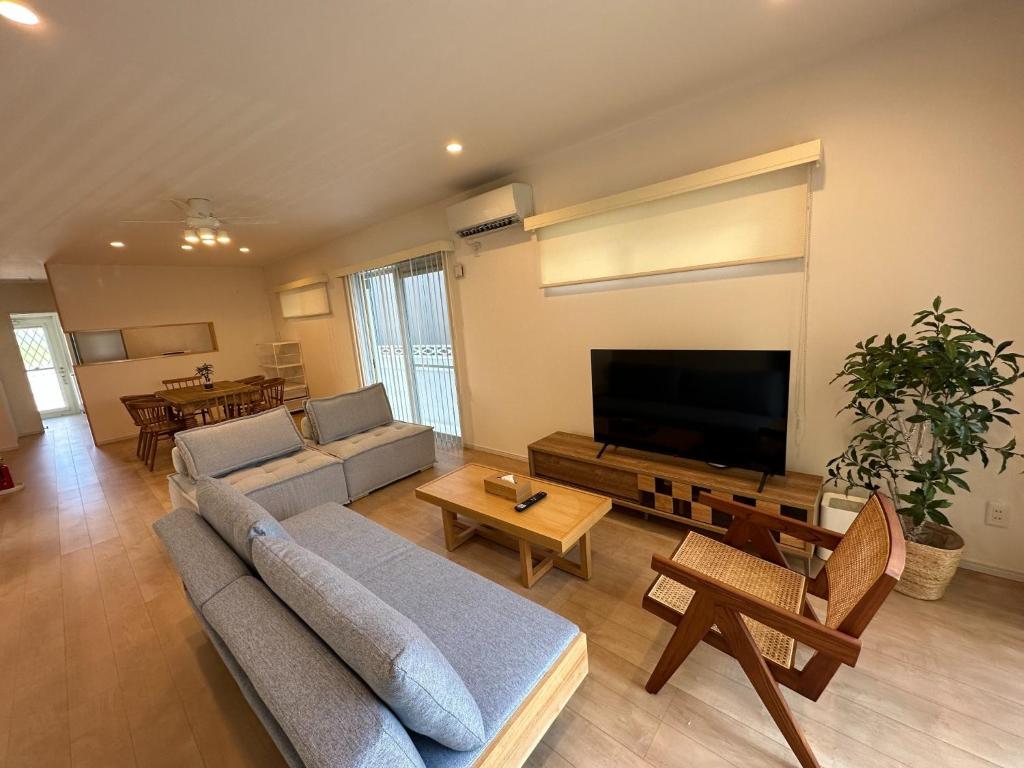 sala de estar con sofá y TV de pantalla plana en Bears Stay Kumejima Villa - Vacation STAY 01040v, en Kumejima