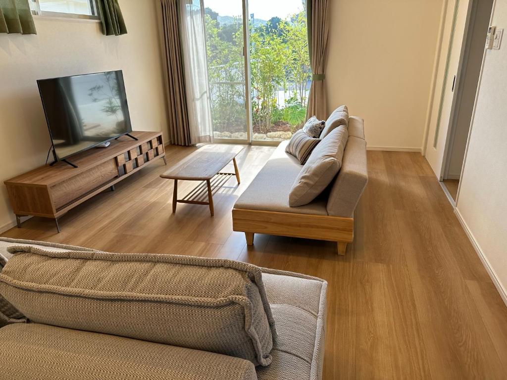 sala de estar con 2 sofás y TV de pantalla plana en Bears Stay Kumejima Villa - Vacation STAY 00998v, en Kumejima