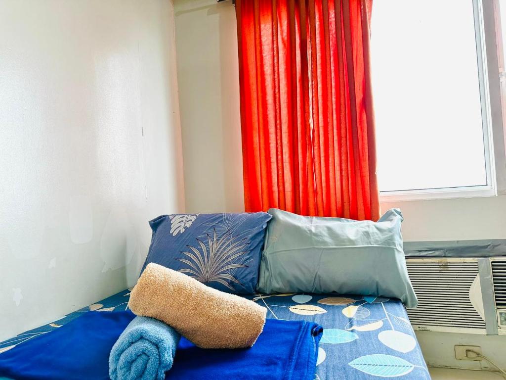 een slaapkamer met een bed met blauwe kussens en een raam bij Sea Residences - Manila Pasay near MOA by Ipe in Manilla