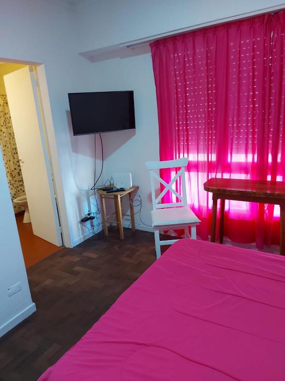 a pink room with a bed and a pink curtain at Depto casique 2pax in Necochea