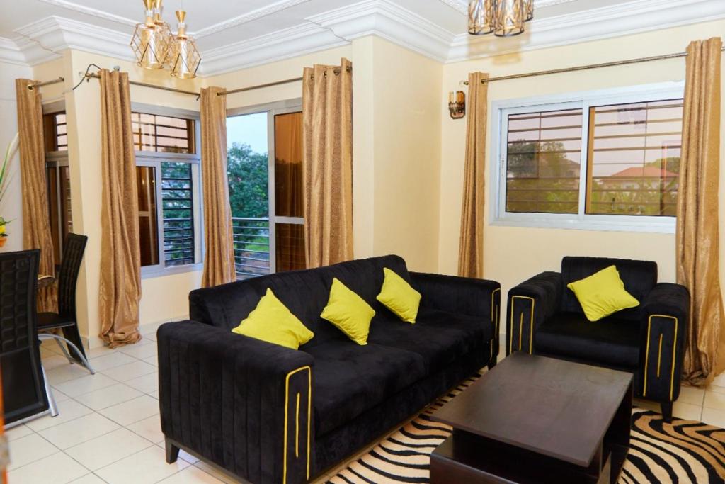 ein Wohnzimmer mit einem schwarzen Sofa und gelben Kissen in der Unterkunft LUXOR RESIDENCE YASSA DOUALA in Ngori