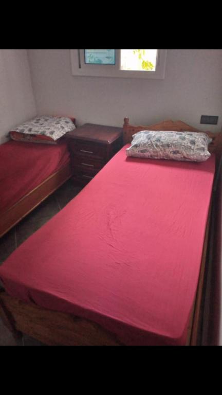 two beds in a small room with red sheets at Appartement à ALHOCEIMA in Al Hoceïma