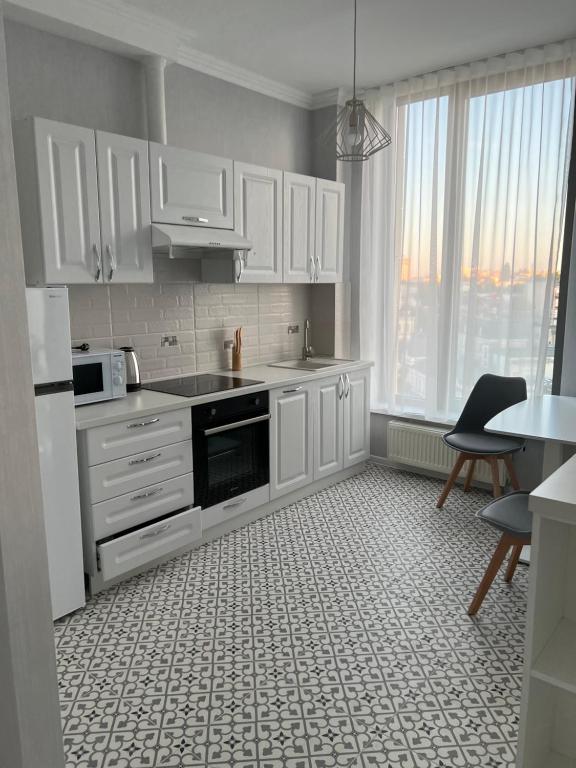 a kitchen with white cabinets and a table and chairs at Crown Plaza Park Luxury Apartment in Chişinău