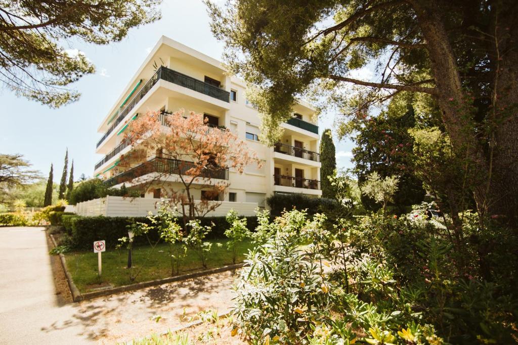 ein großes weißes Gebäude mit vielen Bäumen in der Unterkunft Cozy room on the beach in La Ciotat