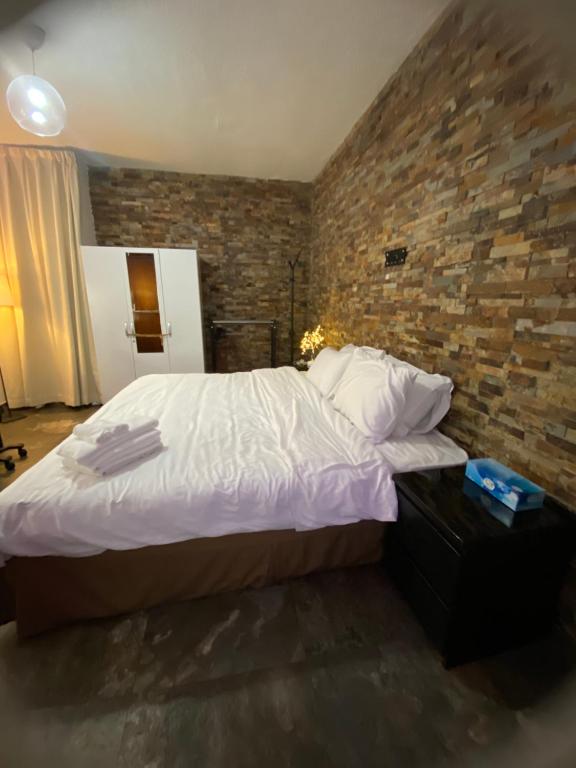1 dormitorio con 1 cama grande y pared de ladrillo en Lilu BnB, en Dubái