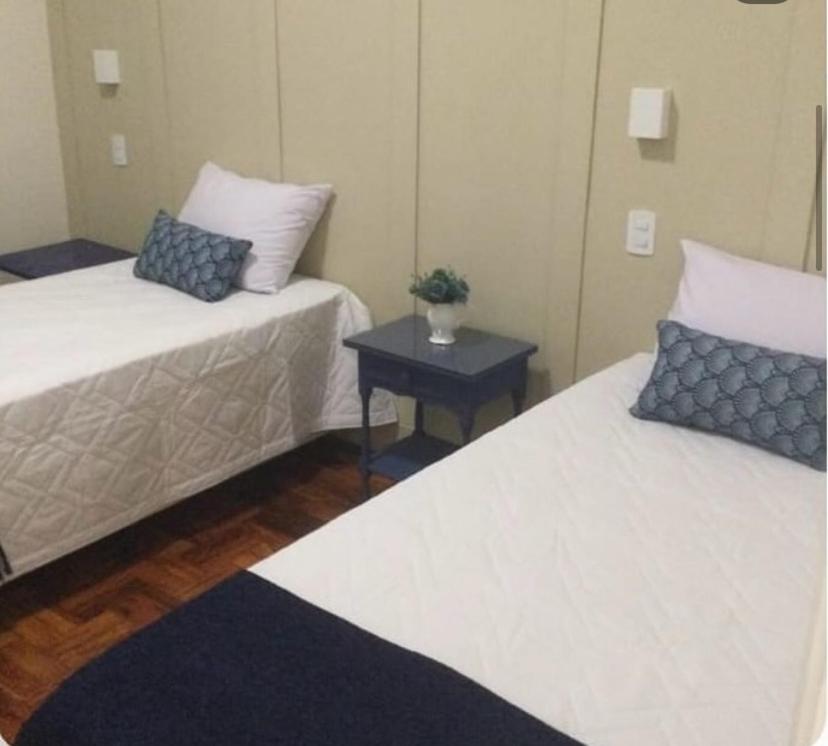 um quarto com duas camas e uma mesa com mesa de cabeceira em Hospedaria das Brotas em Espírito Santo do Pinhal