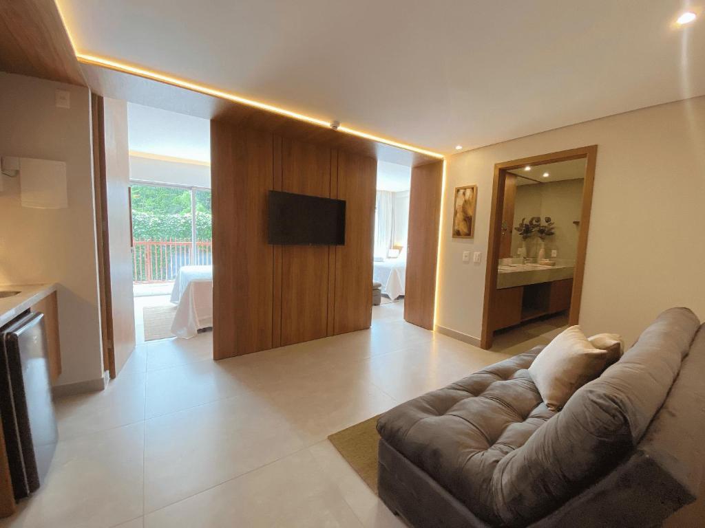 een woonkamer met een bank en een flatscreen-tv bij Flat Île de Pipa Luxxor - By Almare in Pipa