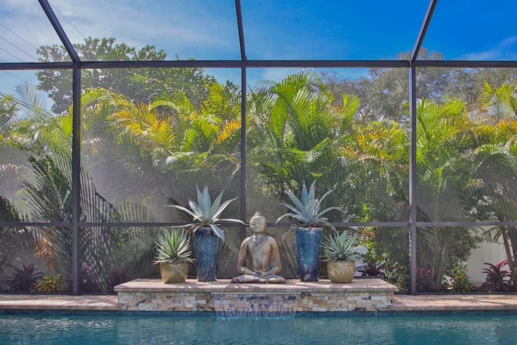 una statua seduta accanto a una piscina con piante di Gorgeous Private Home with Heated Pool a Sarasota