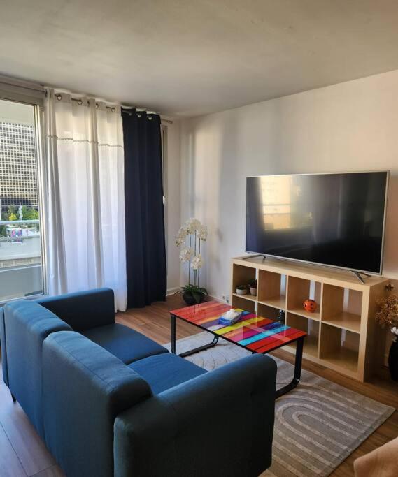 a living room with a blue couch and a flat screen tv at Appartement La Défense in Puteaux