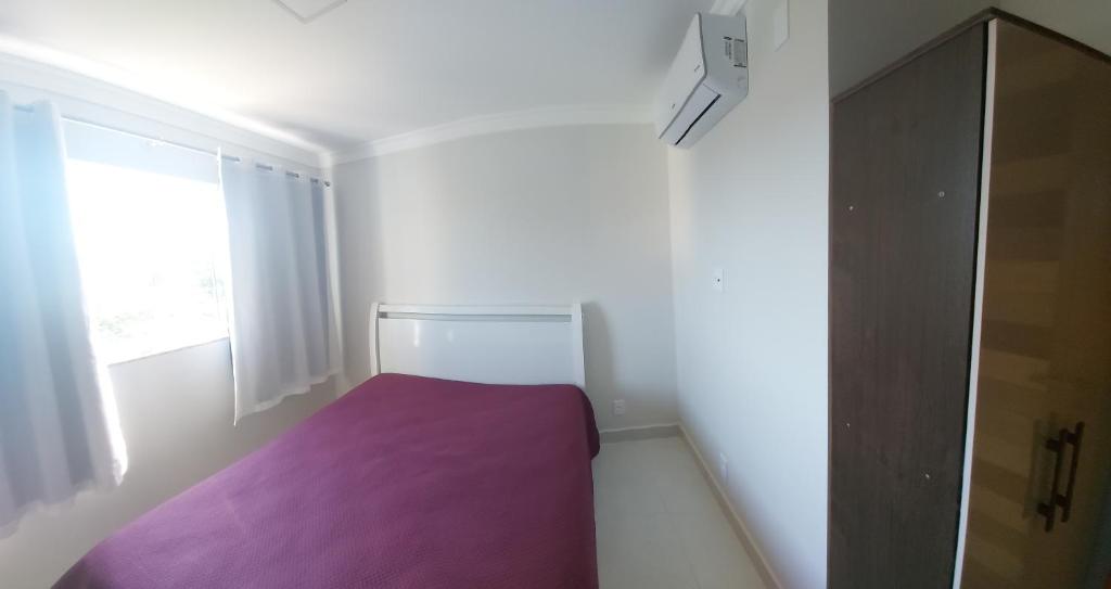 a small bedroom with a purple bed and a window at apartamento para até 5 pessoas in Vila Velha