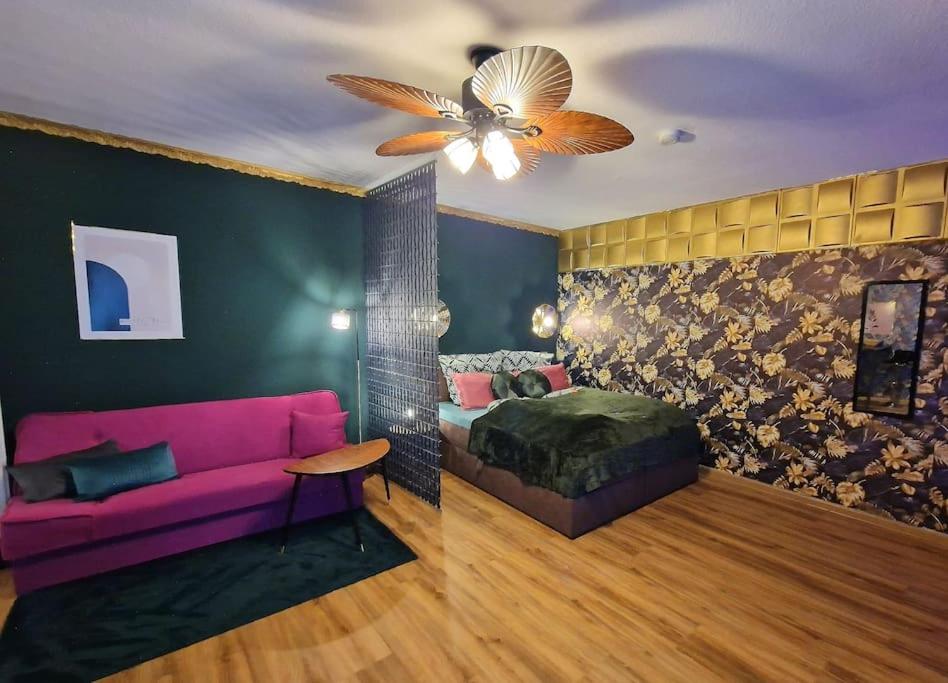 uma sala de estar com um sofá rosa e uma cama em Dark Jungle Suite: Seltersweg Netflix TV & Jumanji em Giessen