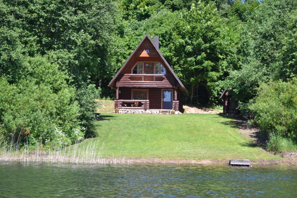 une cabine dans les bois à côté d&#39;une nappe d&#39;eau dans l&#39;établissement Lõõdla Holiday House, à Lümatu