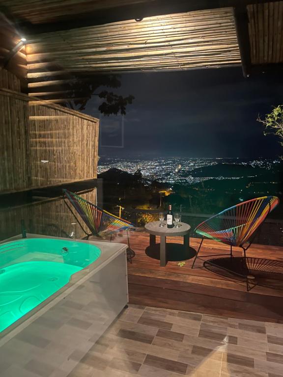 une terrasse avec un bain à remous, des chaises et une table dans l'établissement Romero Glamping y Cabañas, à Cali