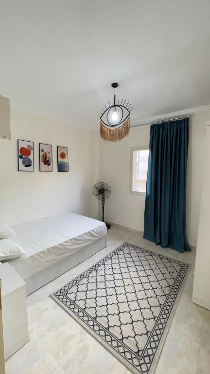 a white bedroom with a bed and a rug at Gardinia city compound, Nasr city in Cairo