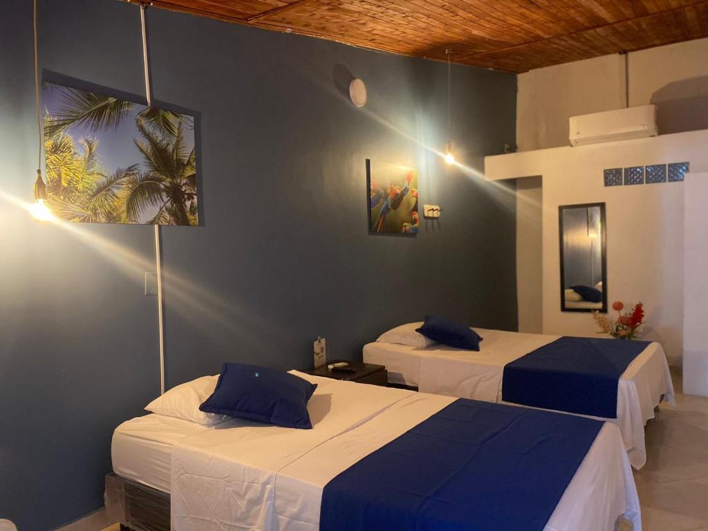twee bedden in een kamer met blauwe muren bij Casa Hotel La Palmera Apartadó in Apartadó