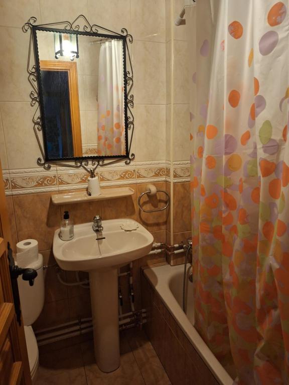 uma casa de banho com um lavatório, um espelho e uma banheira em Hostal el patio restaurante em San Bartolomé de Pinares