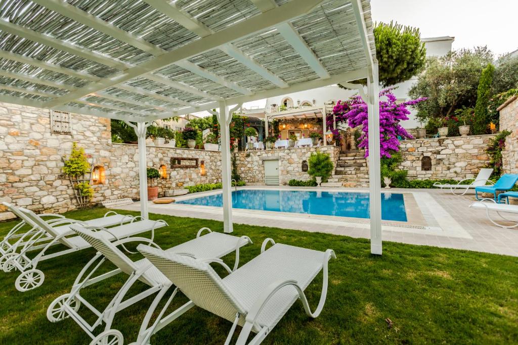 a patio with white chairs and a swimming pool at Ipekyol Hotel in Cesme