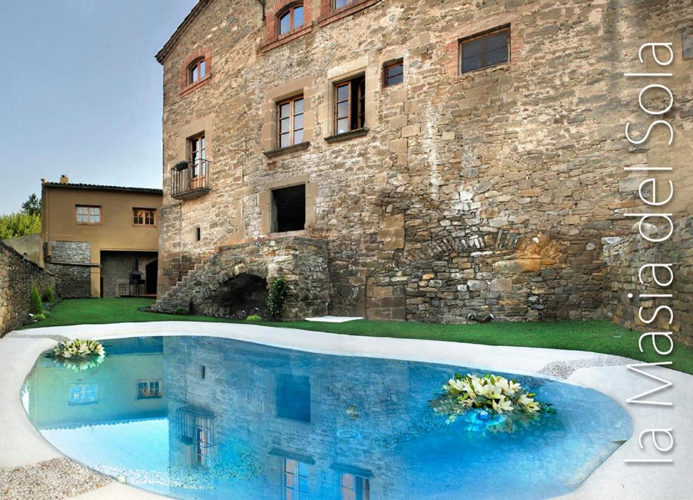 ein großes Steingebäude mit einem Pool davor in der Unterkunft Fonda La Masia Del Sola in Monistrol de Calders