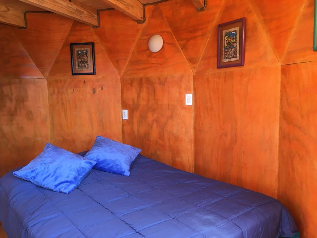 Cama en habitación de madera con almohadas azules en Hermoso Domo con vista al Mar en Horcón en Horcón
