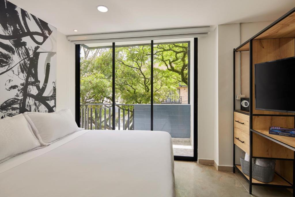 a bedroom with a bed and a large window at Altio Hotel in Cali
