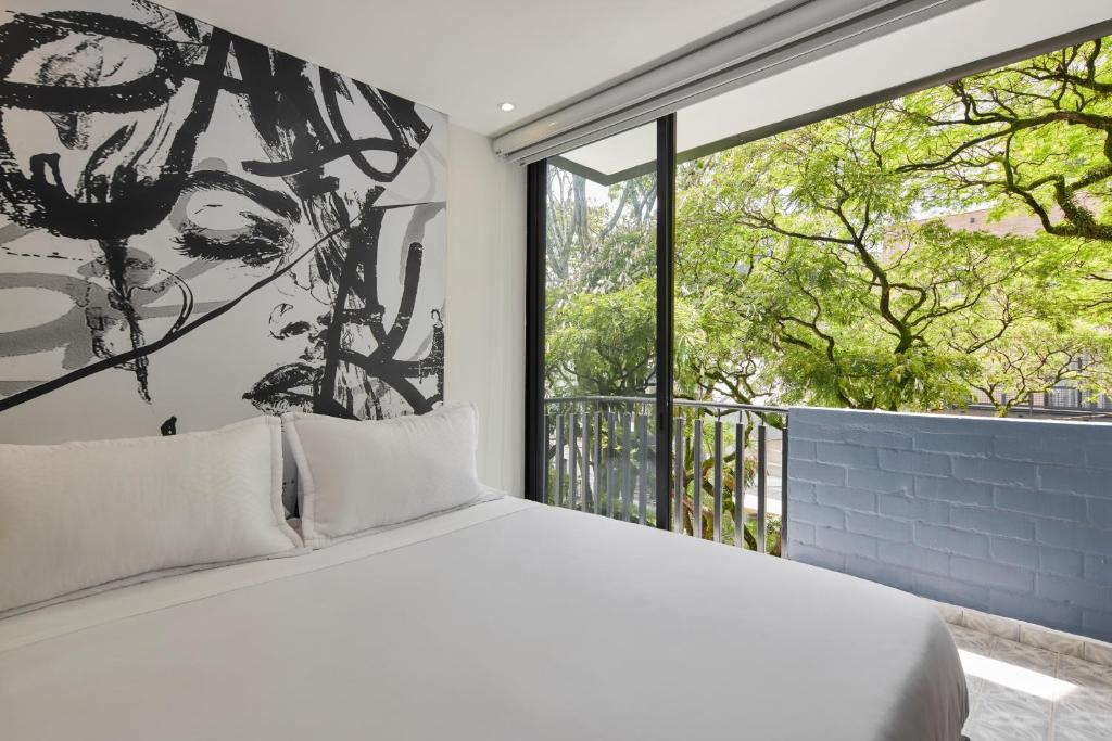 a bedroom with a bed and a large window at Altio Hotel in Cali