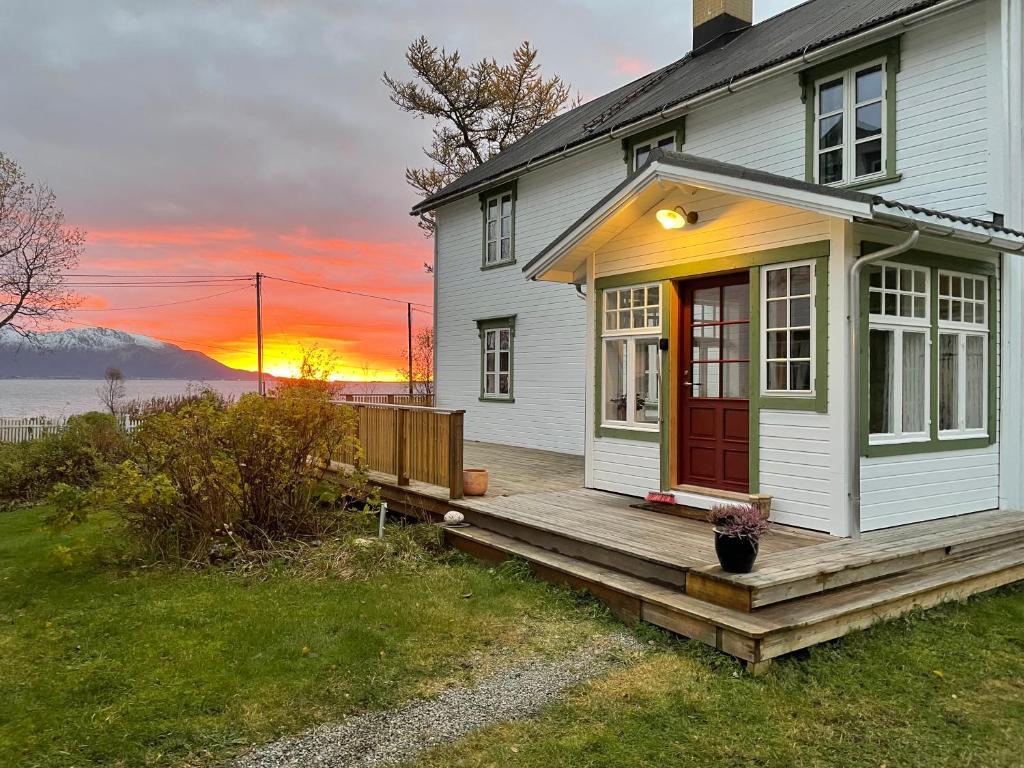 a house with a deck with a sunset in the background at Bårdstua in Stokmarknes