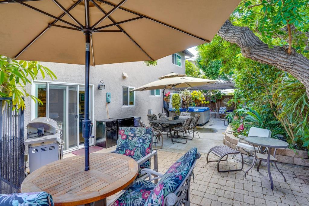 un tavolo e sedie in legno con ombrellone su un patio di Costa Mesa Rental with Private Hot Tub and Fire Pit! a Costa Mesa
