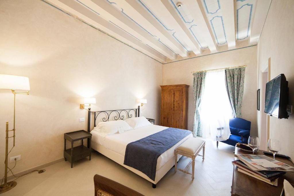 a bedroom with a bed and a tv and a window at Algilà Ortigia Charme Hotel in Siracusa