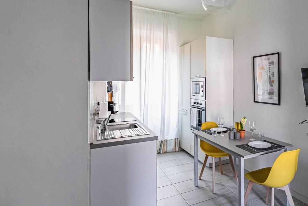 - une cuisine blanche avec une table et des chaises jaunes dans l'établissement Casa Elena - vicino al Castello - by Host4U, à Pavia