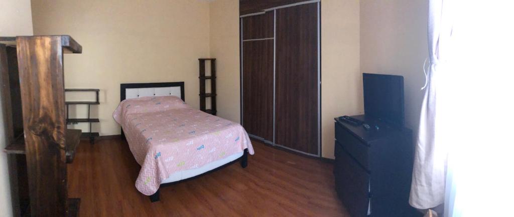 a bedroom with a small bed and a tv at Garzonier in Cochabamba