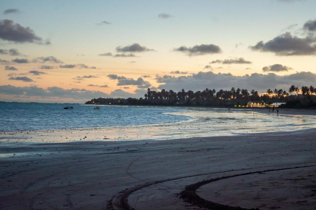 einen Strand bei Sonnenuntergang mit Fußabdrücken im Sand in der Unterkunft Excelente aparamento em Milagres à 100 metros da Praia in São Miguel dos Milagres
