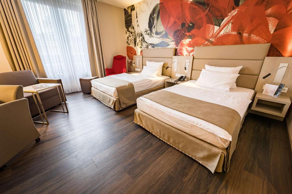une chambre d'hôtel avec deux lits et un canapé dans l'établissement First Inn Hotel Zwickau, à Zwickau