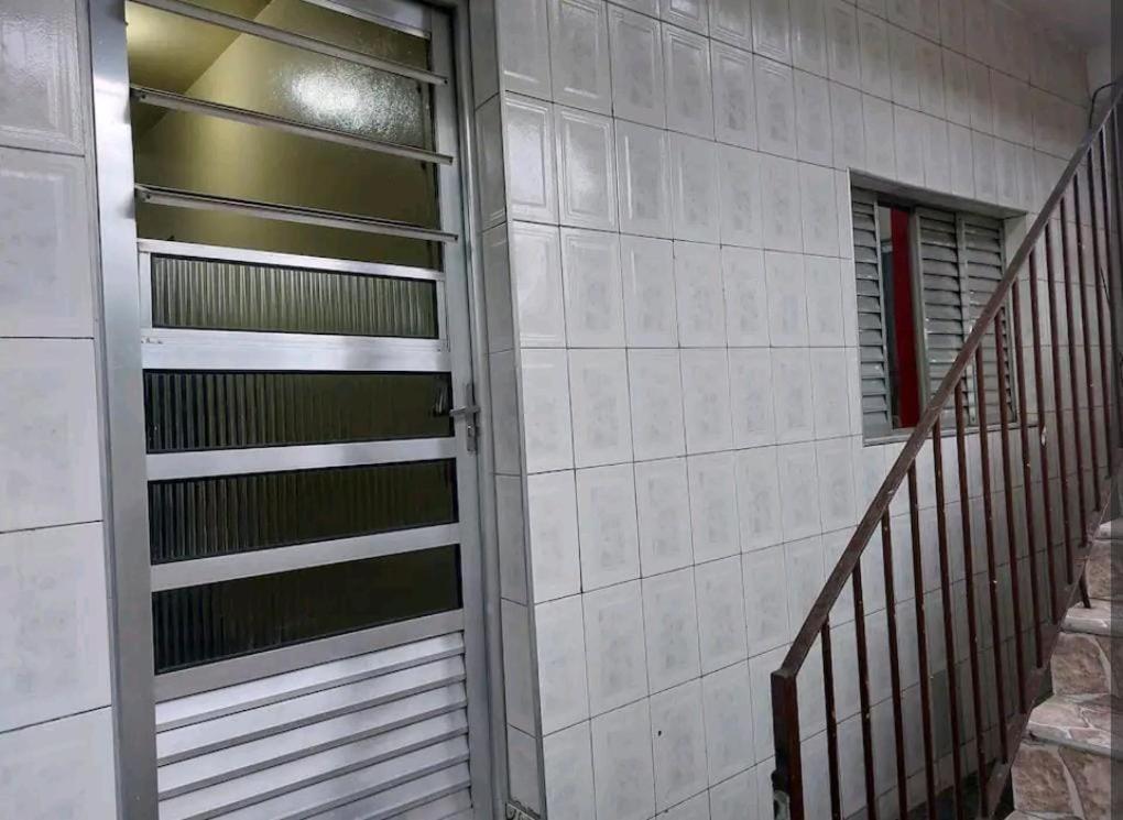 eine Tür zu einem Gebäude mit einer Treppe daneben in der Unterkunft Casa no ABC perto de São Paulo Expo e Jd botanico in São Paulo