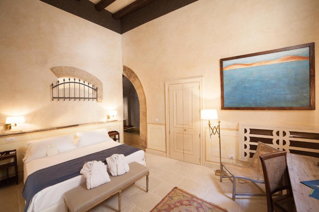 a bedroom with a bed and a chair and a painting at Algilà Ortigia Charme Hotel in Siracusa