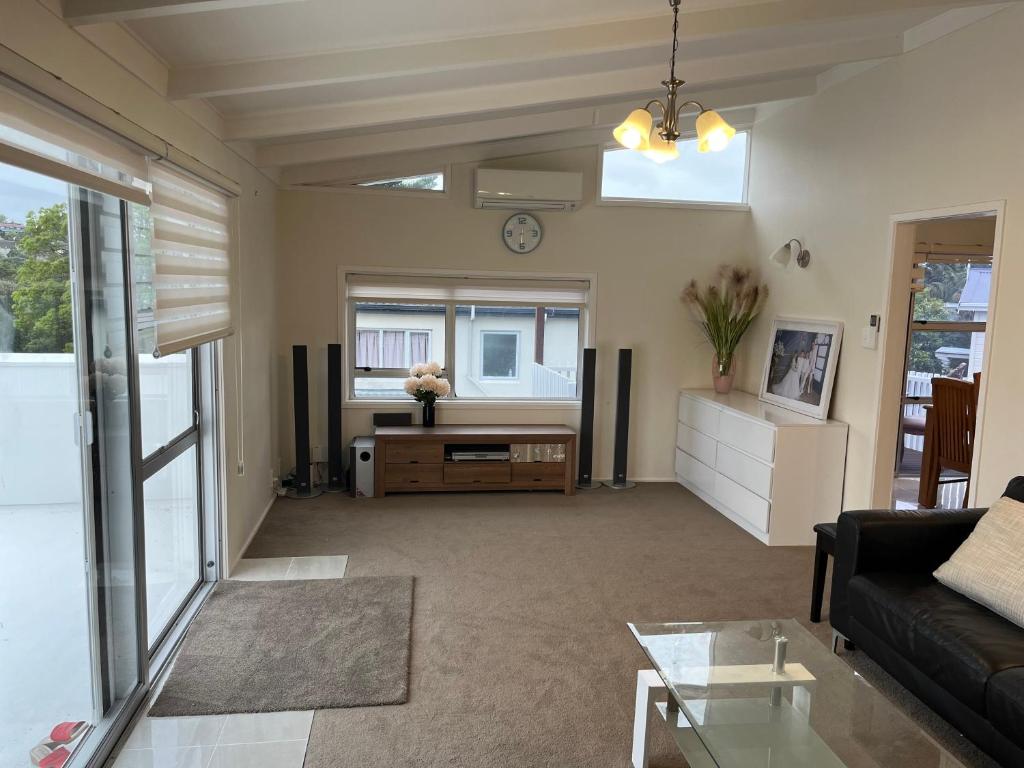 a living room with a couch and a clock on the wall at Hillcrest Homestay, NorthShore, Auckland in Auckland