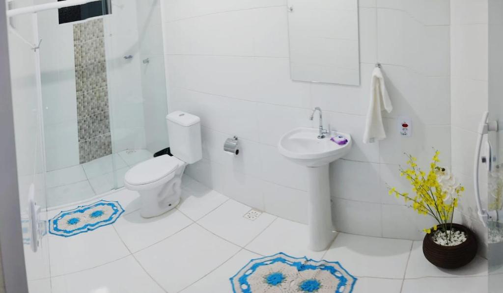 a white bathroom with a toilet and a sink at Pousada Recanto da Preguiça in Jarinu