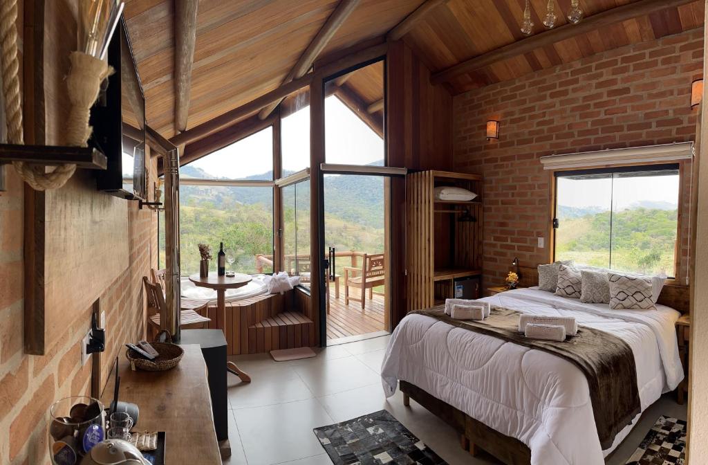 een slaapkamer met een groot bed en een groot raam bij Pousada Ho'oponopono Chalets & Wine in Sapucaí-Mirim